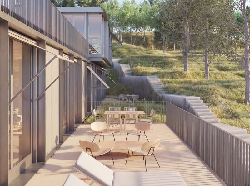 modern building with glass walls, outdoor dining area, wooden deck, stairs leading to a grassy hill