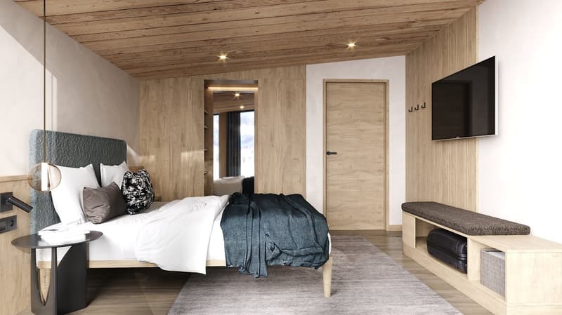 Wooden walls and ceiling, bed with white bedspread, beige rug, TV on wall, wooden bench with cushioned seat