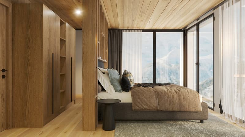 bedroom with wooden walls, beige rug, large bed, nightstand, and tall windows with views of mountains