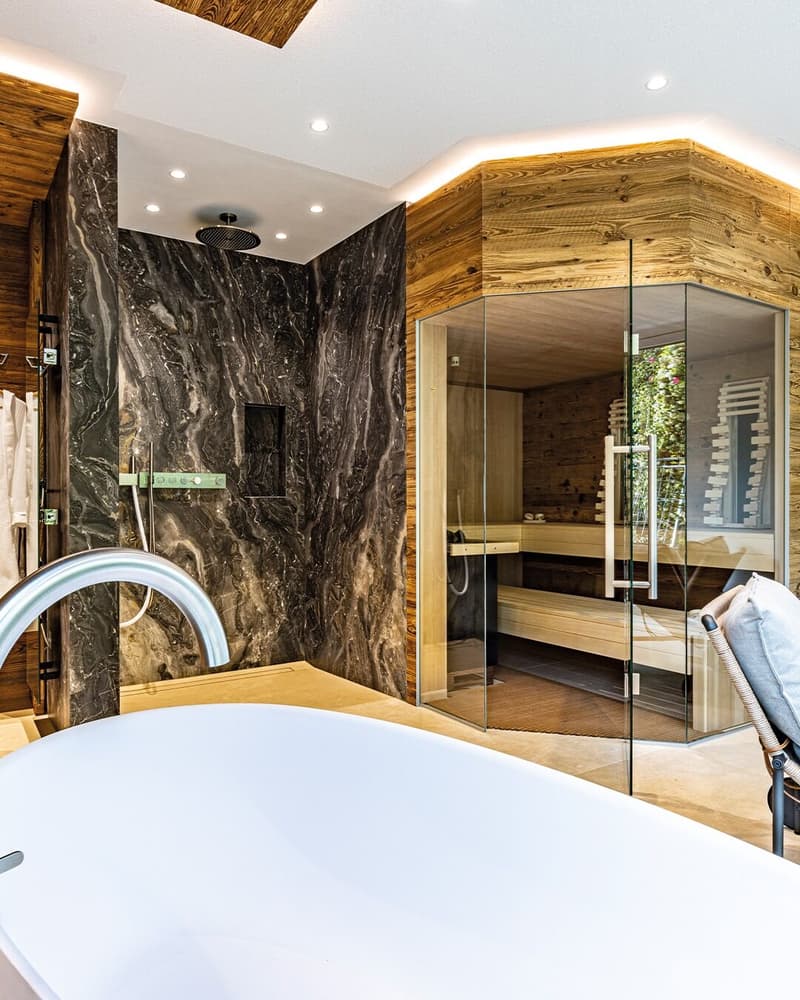 Large marble bathroom with tub, shower, sauna, and wooden wall