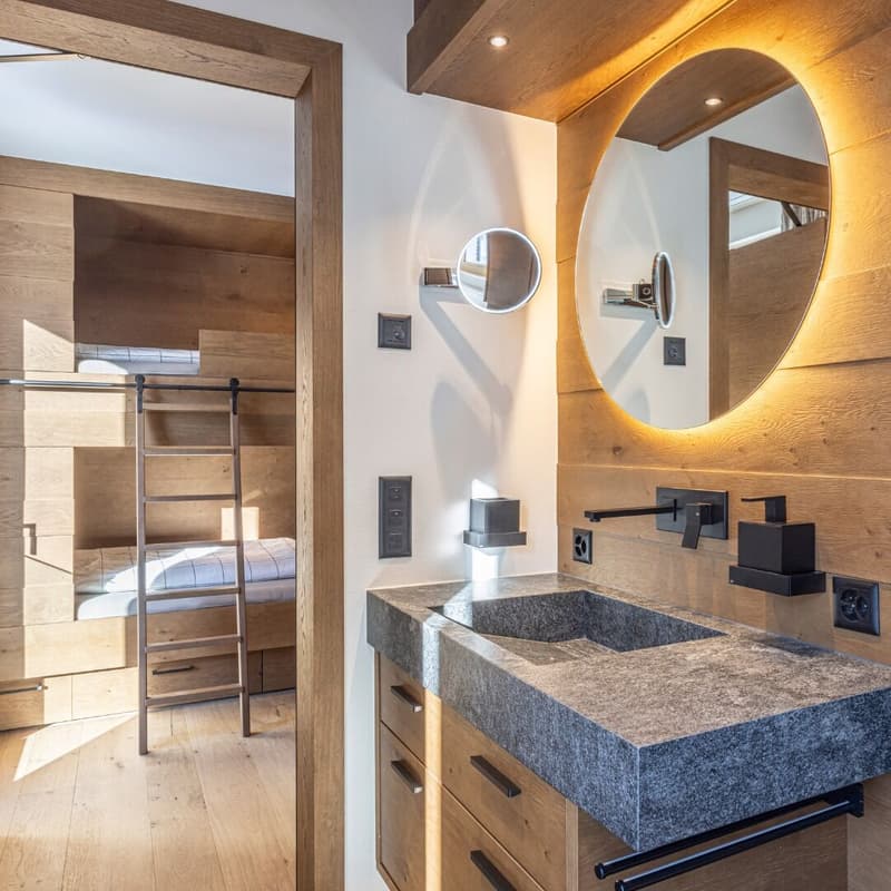 Bathroom with granite sink, wooden wall, large mirror, open bunk bed