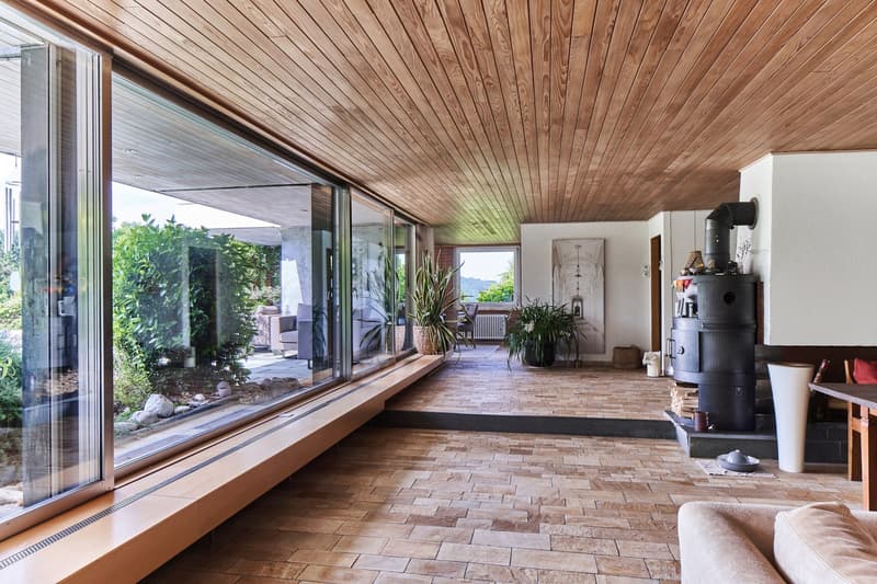 large glass windows, wooden ceiling, wood flooring, large glass doors, living area, fireplace