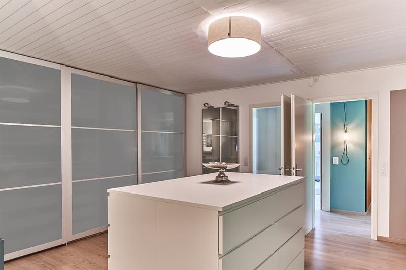 modern kitchen, white cabinets, gray drawers, central island with statue, mirror and sliding doors