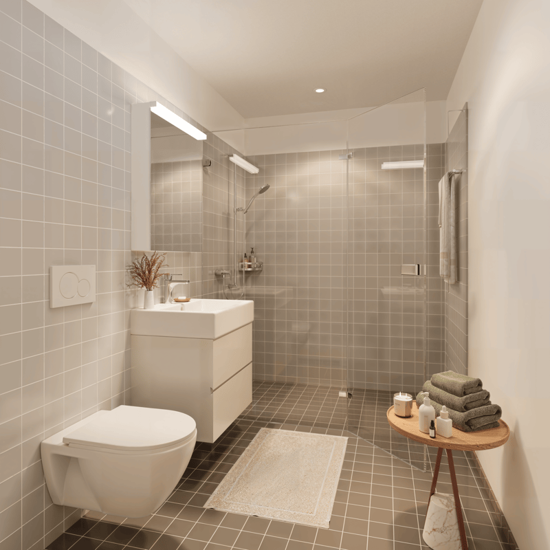 Modern bathroom with white tiles, white toilet, white sink, glass shower enclosure, towel rack, and a small table with towels and toiletries.