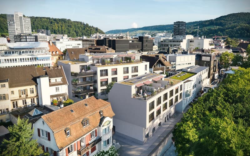 Modern apartment building with multiple floors, green roofs, balconies, and terraces.