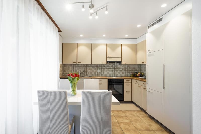 Dining table, kitchen cabinets, counter, oven, refrigerator, sink