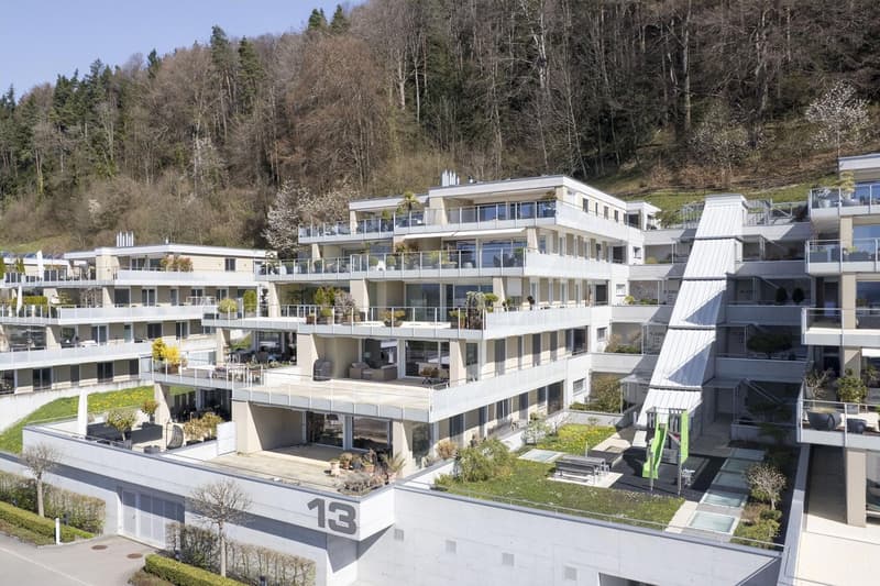 Modern multi-story building with multiple balconies, green roofs, and a playground