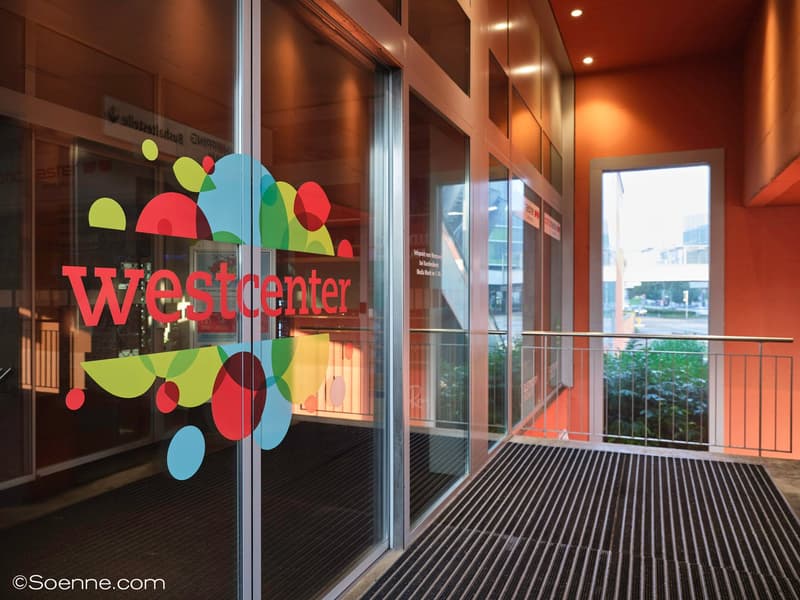 Entrance glass door with Westcenter logo, metal railing, walkway leading to building
