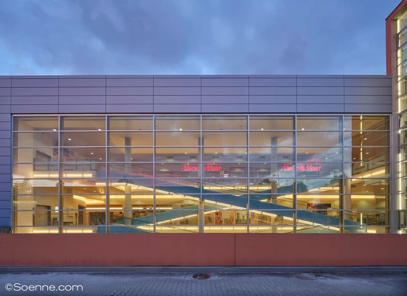 Large modern glass front, signage, internal escalator visible through glass
