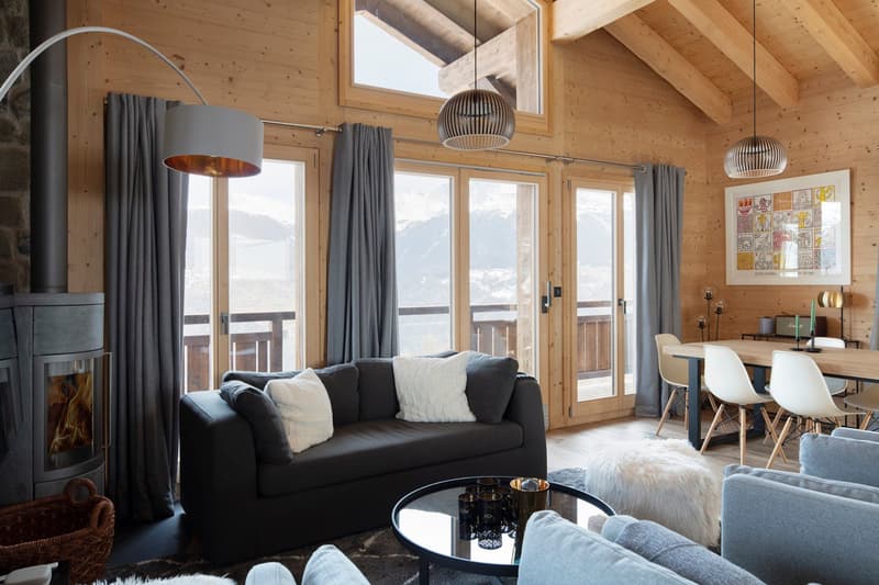 wooden walls, fireplace, large windows, couch, table, chairs, lamps, artwork