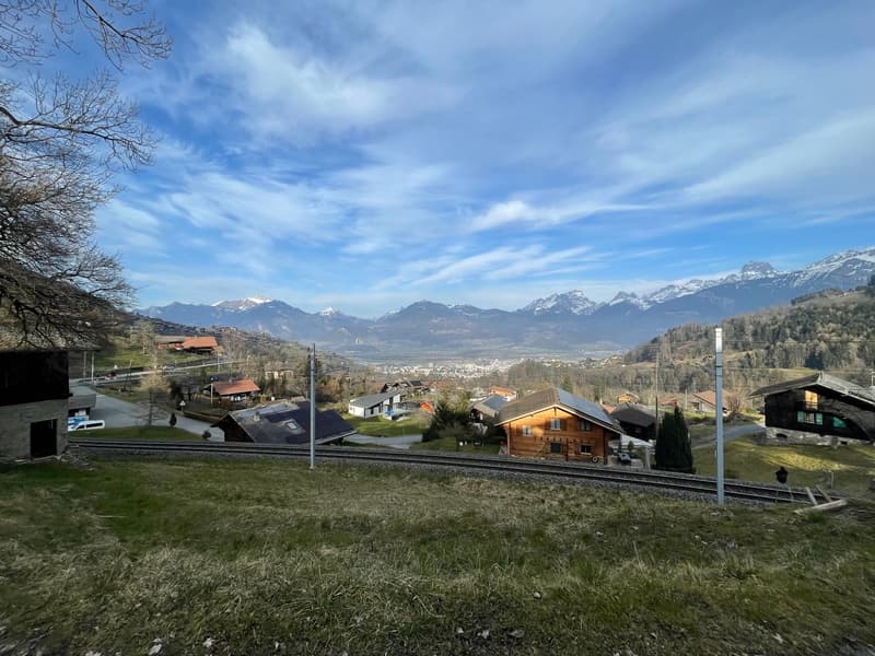 Rural valley with mountains, houses, and a railway