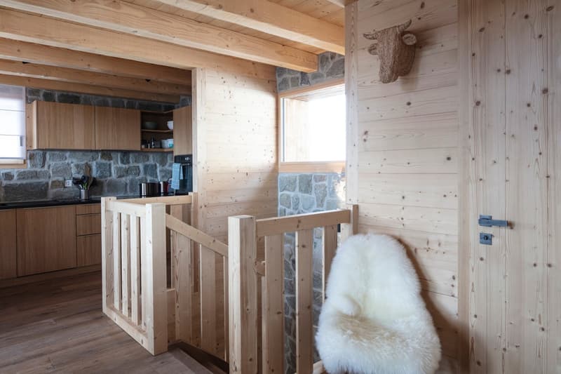 wooden interior, wooden staircase, wooden flooring, stone wall, wooden cabinet, white fur chair
