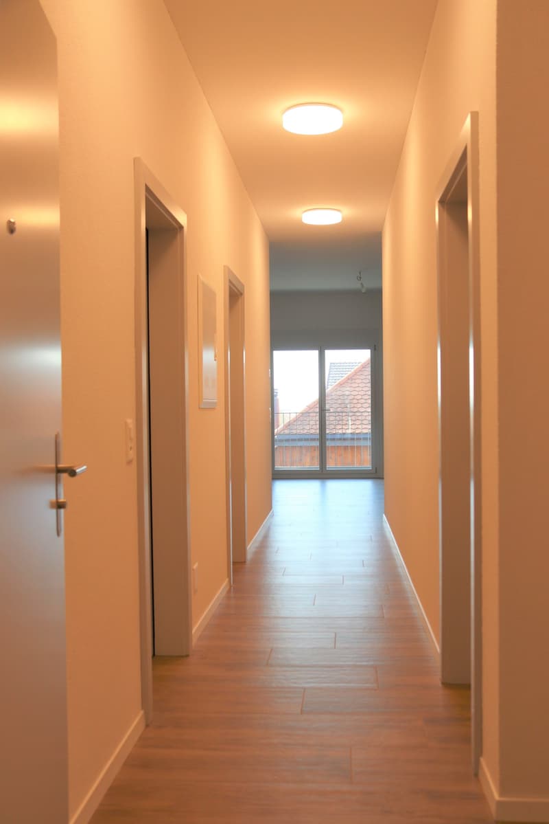 long corridor, white walls, tiled floor, light ceiling, sliding door, balcony