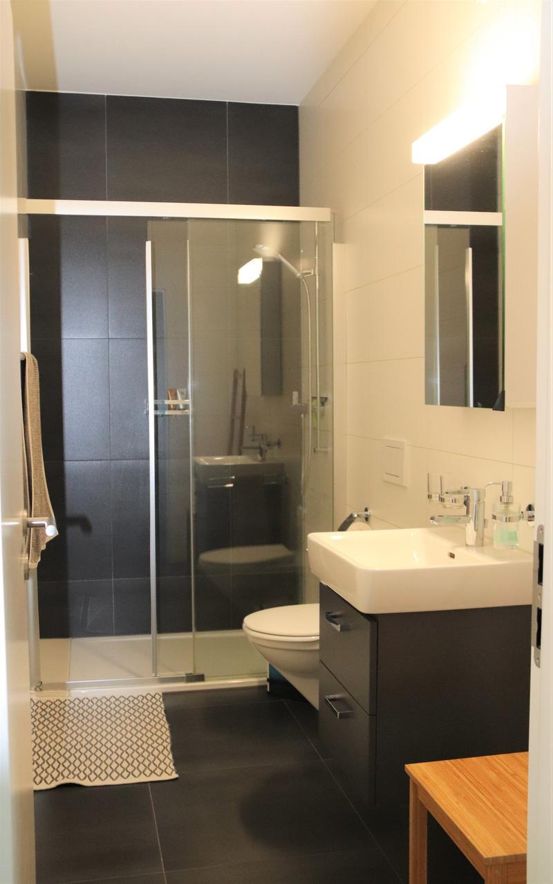 Bathroom with shower, toilet, sink, mirror, and wooden stool