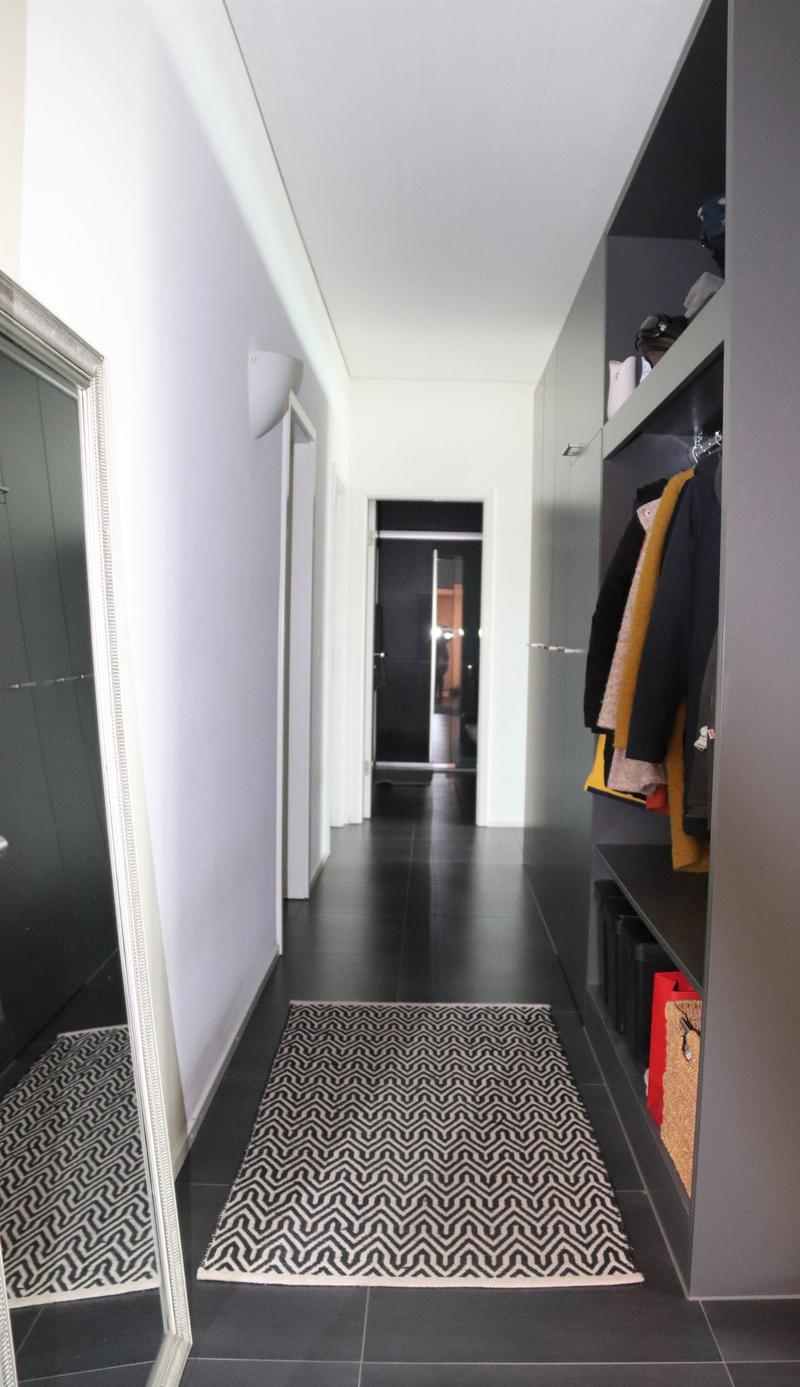 hallway with black tiles, large mirror, large rug, built-in wardrobe