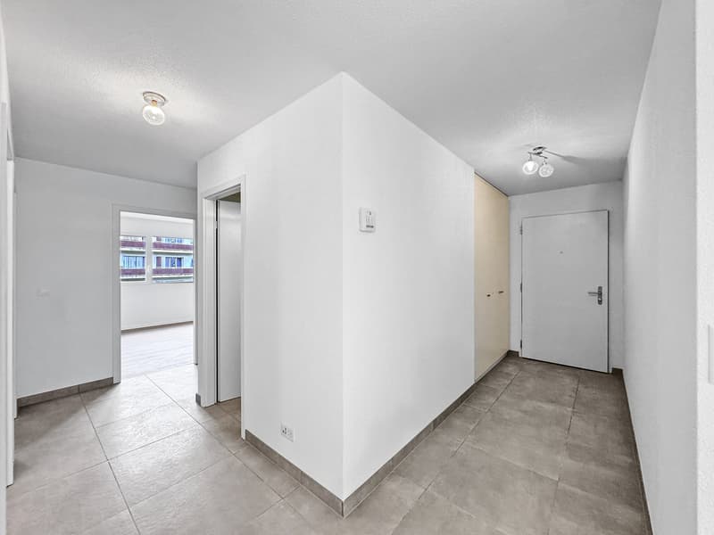 Empty room, white walls, tiled floor, two doors, small windows.