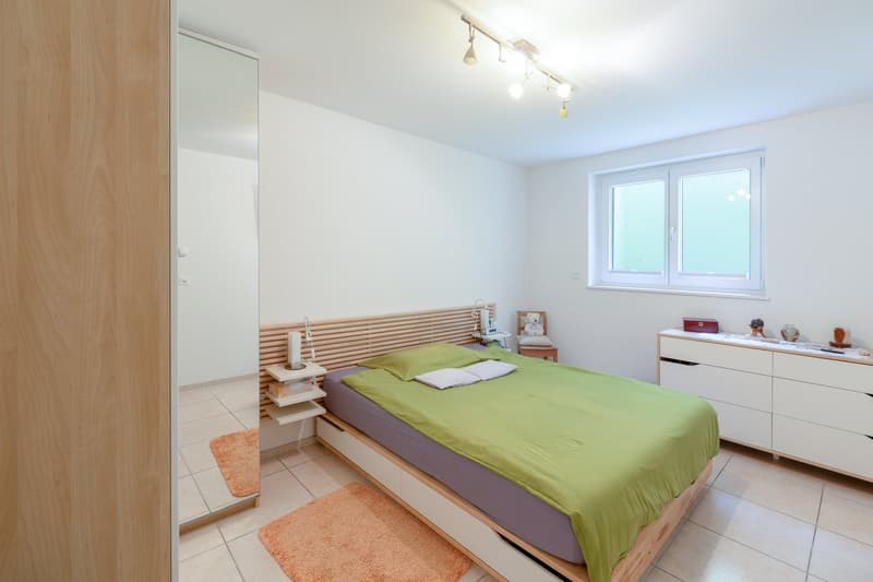 Bedroom with bed, nightstands, mirror, window, and wooden floor