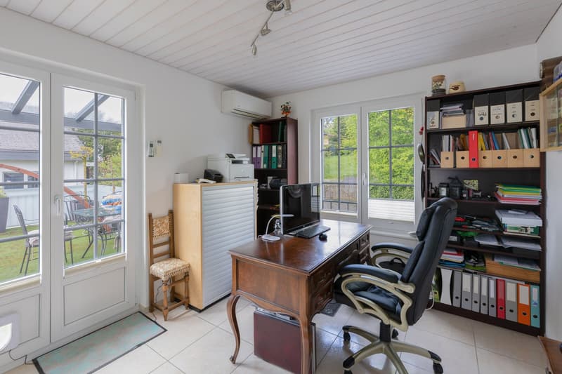 Office room with desk, chair, printer, bookshelves, and large windows