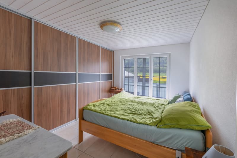 bedroom with bed, wooden wardrobe, tiled floor, window with view