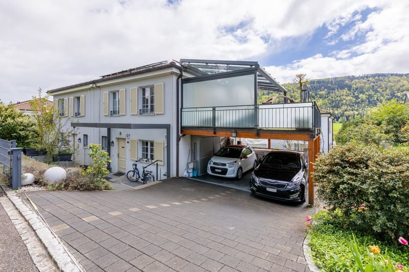 2 story house, white exterior, glass garage, 2 cars parked, bicycles, paved driveway