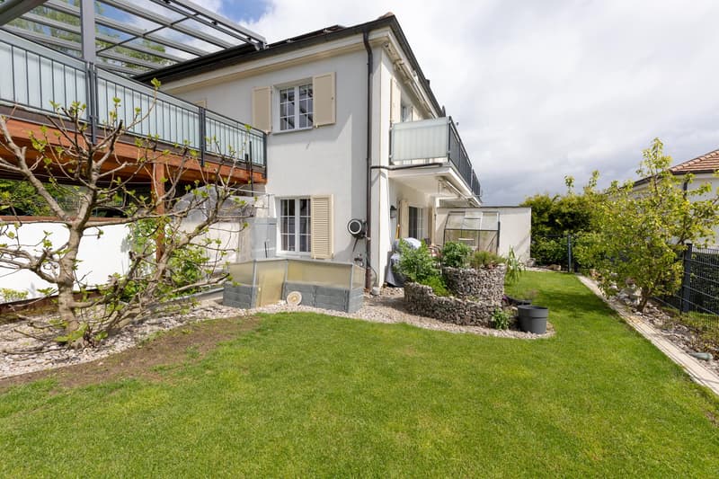 2 story house, white exterior, glass windows, balcony, garden with grass and plants
