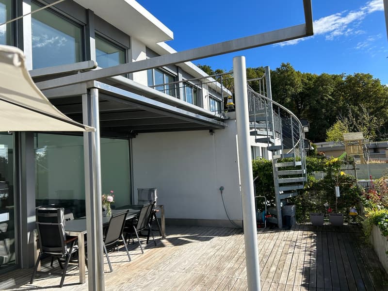 White building, large windows, spiral staircase, spiral metal railing, outdoor seating area, metal railings, spiral stairs, garden view
