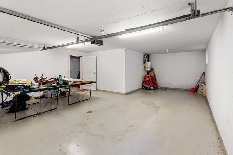 Empty garage with white walls, two tables, and various tools and equipment
