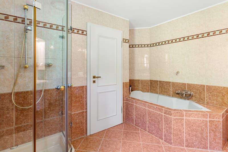 Bathroom with a bathtub, shower, and tiled walls and floors.