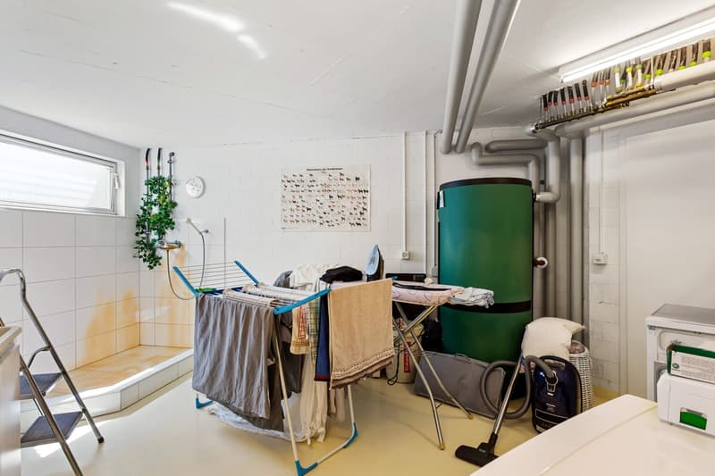 Laundry room with washing machine, drying rack, iron board, and storage boxes