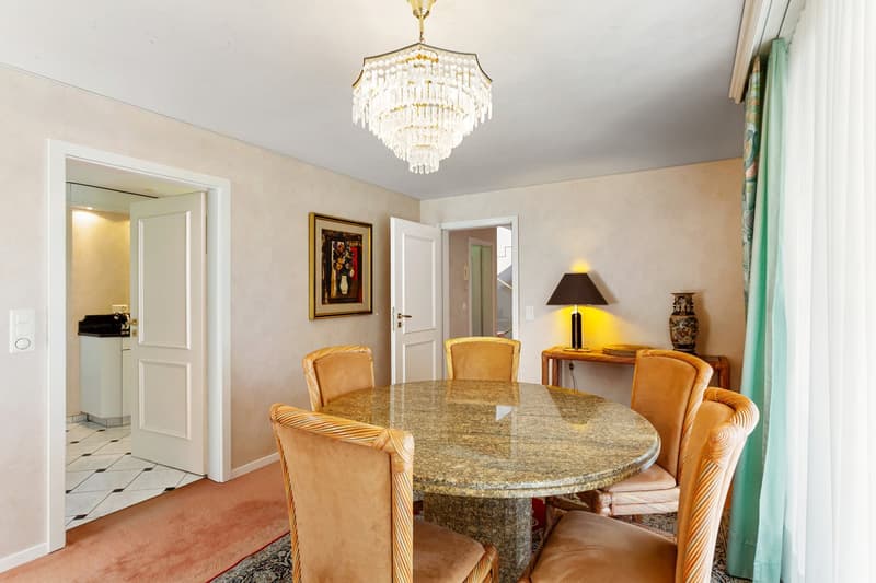Dining room with round table, 6 chairs, chandelier, side table with lamp, picture frame, and vase