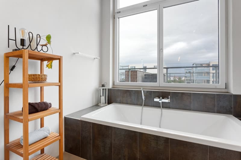 Bathroom with bathtub, wooden shelf, and large window