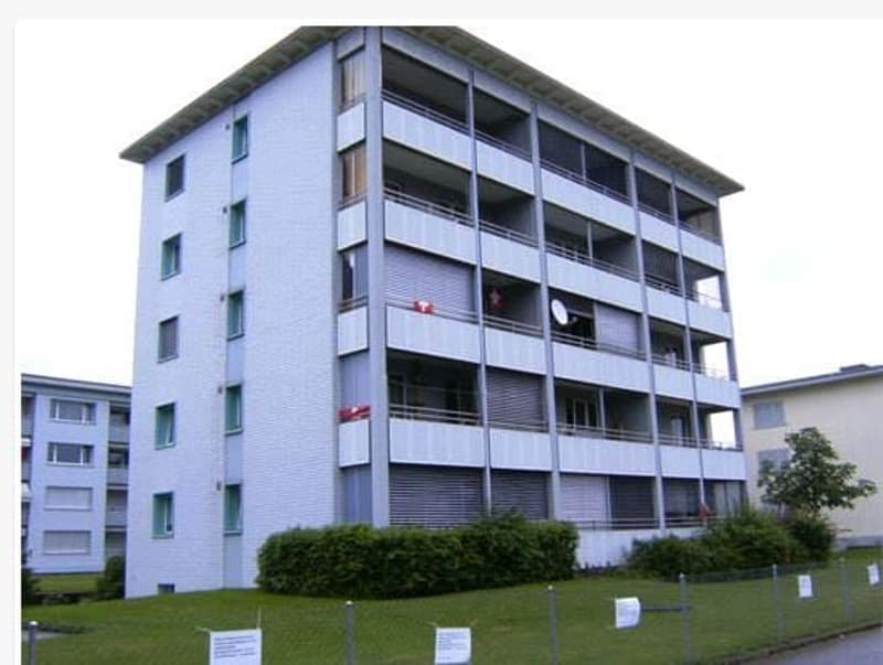 Multi-story apartment building, white exterior, many windows, balconies