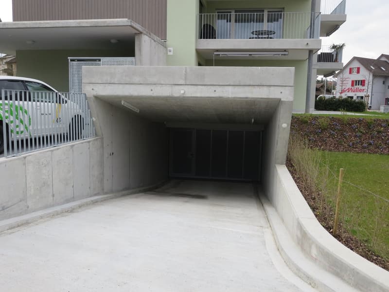 Underground garage with a vehicle parking underneath a raised ground floor of an apartment building