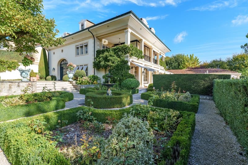 manicured hedges, gravel pathway, geometric garden layout, garden with a fountain, flower vases, trees, and plants