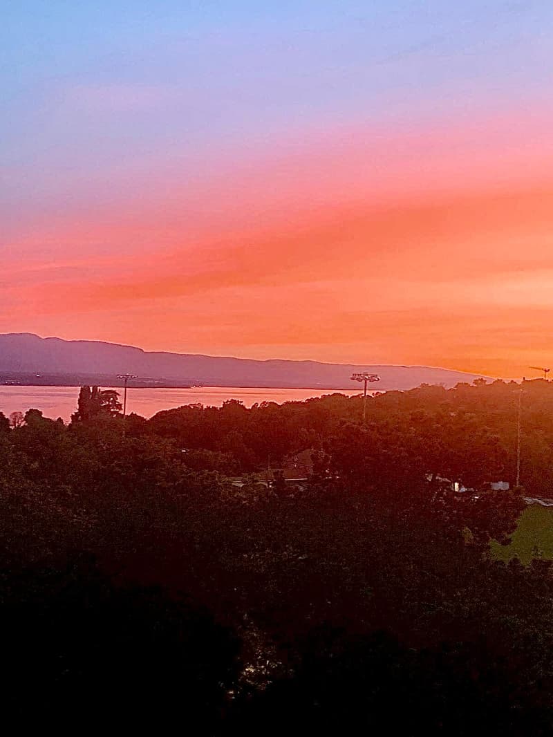 Sunset over mountains, with lake and city in the distance