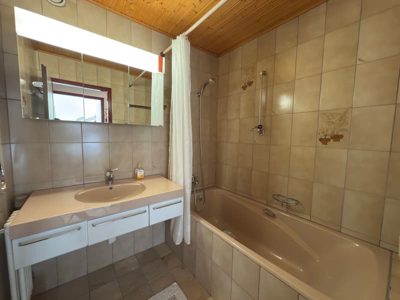 tiled walls, wooden ceiling, sink with mirror, bathtub, shower with curtain, towel rack