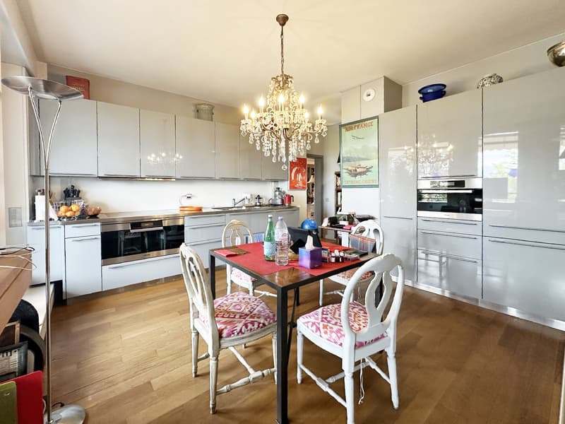 Chandelier, dining table, white chairs, chandelier, microwave, dishwasher, wooden floor, white cabinets, built-in oven, countertop, sink, faucet