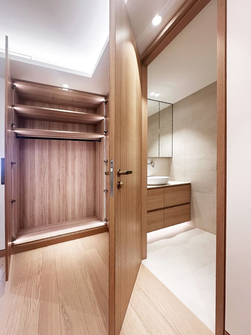 walk-in closet with wooden shelves, white sink, mirror, wooden cabinet, wooden flooring