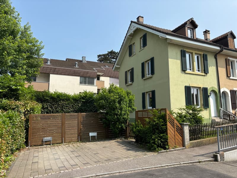 2 story house, yellow facade, brown roof, wooden fences, garden, driveway