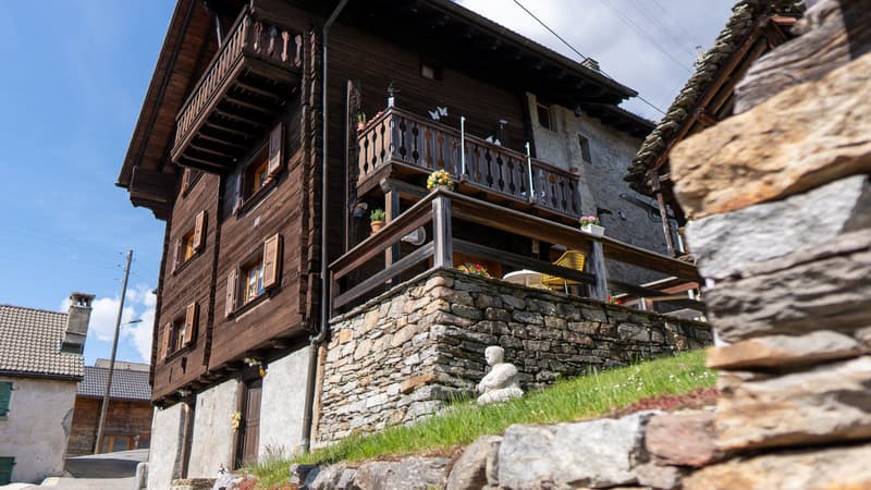 wooden exterior, stone wall, balcony, multiple windows, plants, yellow chairs