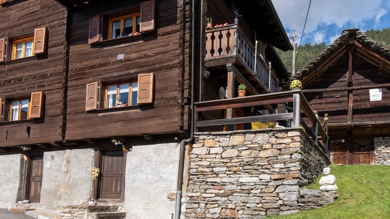 wooden exterior, stone wall, wooden balcony, multiple windows, wooden door, small garden