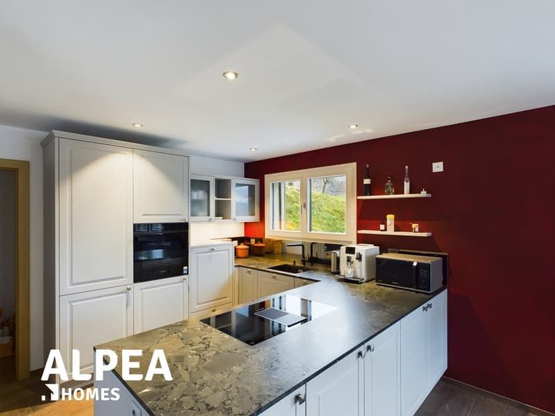 Modern kitchen with granite countertop, gas stove, microwave, wine cooler, and a black oven.