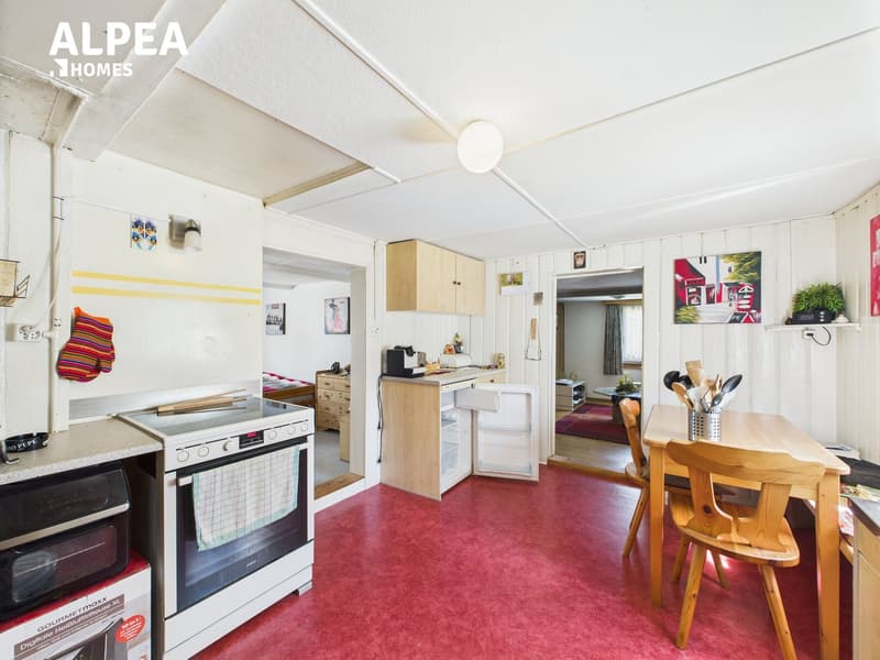 Modern interior of a living room with kitchen area, open shelves, dining table, white appliances