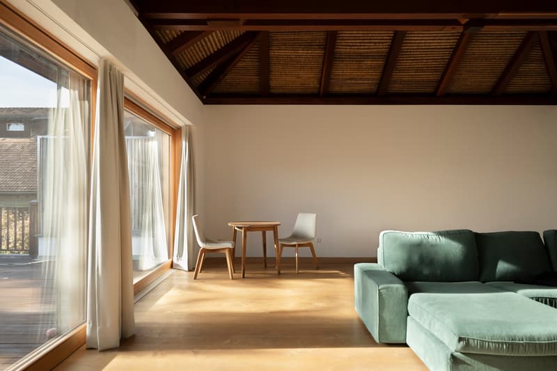 large windows, wooden floor, wooden table, chairs, green sofa, balcony