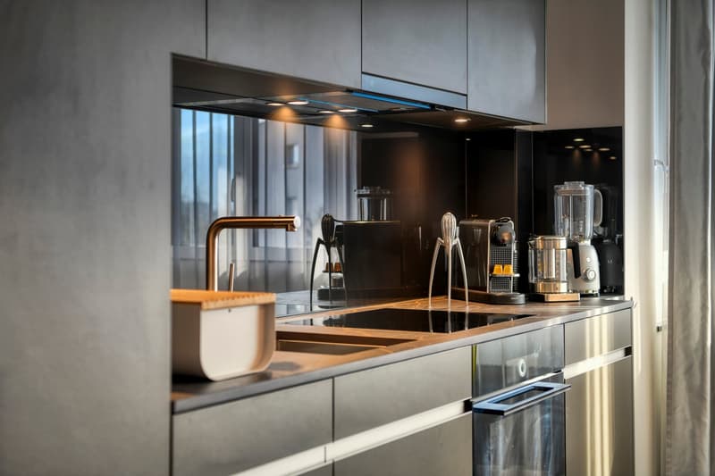 Modern kitchen with dark cabinets, stainless steel appliances, copper faucet, and kitchen gadgets on the counter