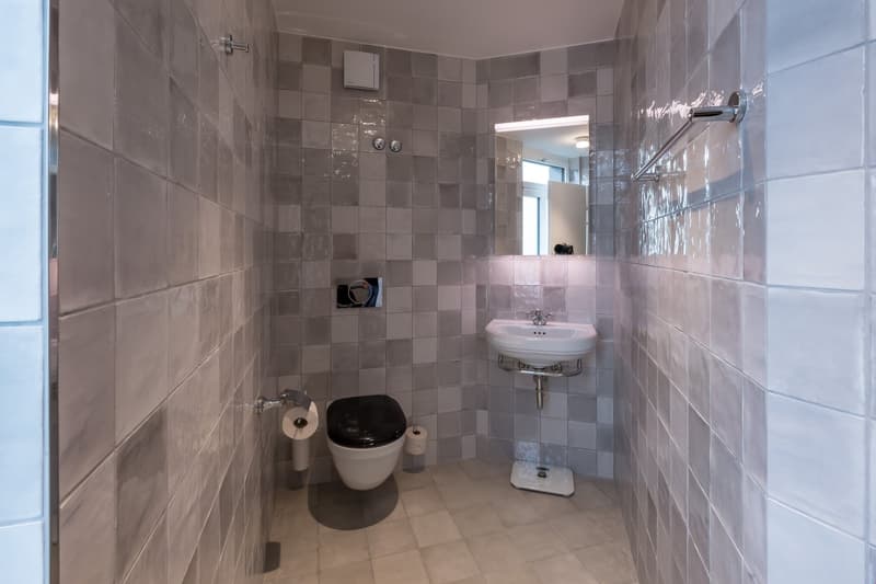 Tiled bathroom with a toilet, sink, and washing machine