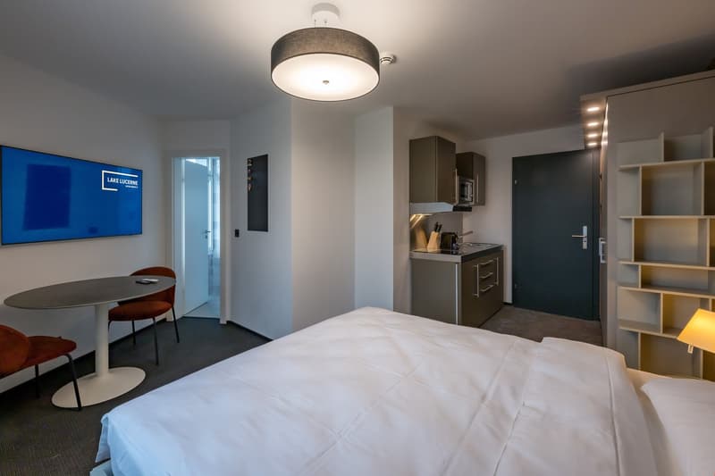 large bed, 2 chairs, table, kitchenette with microwave, flat screen tv