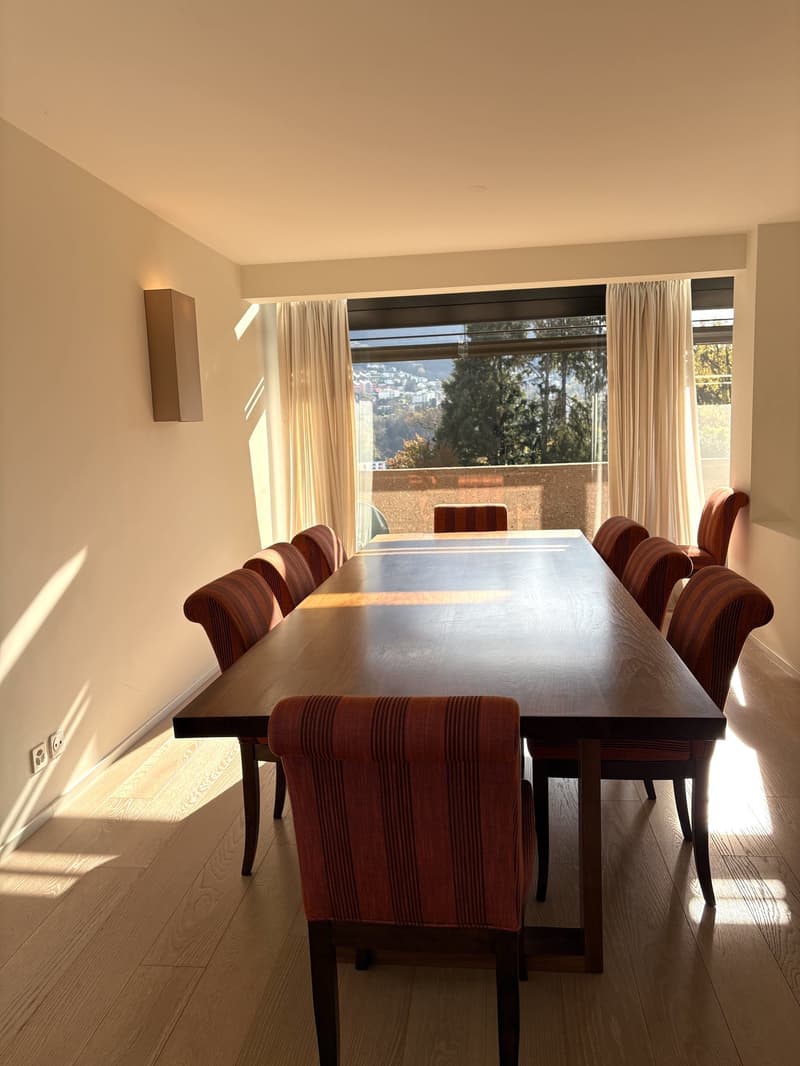 Dining room with large windows, wooden dining table, chairs, hardwood floor, balcony with a city view
