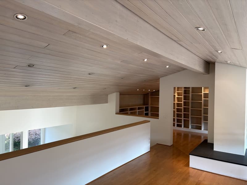 Wooden floor, white walls, recessed ceiling lights, white railing, cabinets