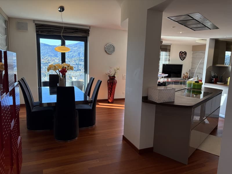 wooden floors, table with 6 chairs, flowers, wall with clock and decorations, open kitchen, kitchen counter with TV